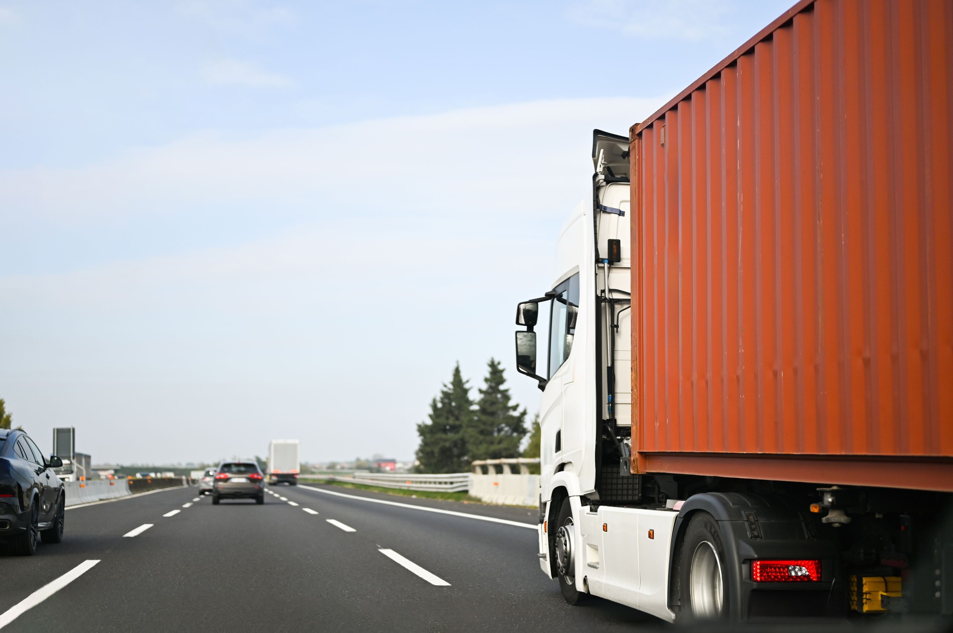 White semi-truck carrying cargo container traveling on highway